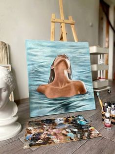 a painting of a woman's head in the water with paintbrushes next to it