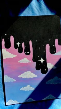 a painting with clouds and stars hanging from it's sides on a blue background