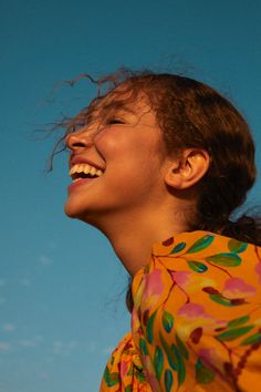 a woman with her hair blowing in the wind and smiling at something she is holding