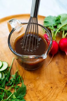 some radishes and cucumbers on a cutting board with a whisk