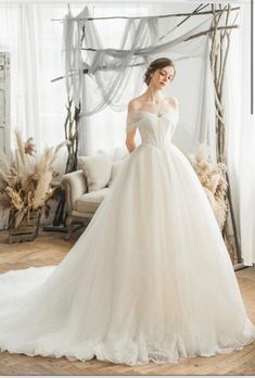 a woman in a white wedding dress standing on a wooden floor next to a window