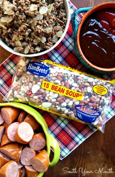 ingredients to make bean soup laid out on a plaid cloth, including carrots, beans, and sausage