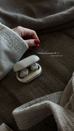 a woman's hand on top of a pair of earbuds sitting on the floor