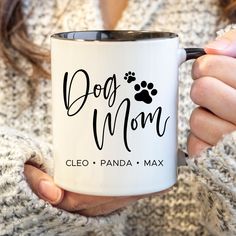 a woman holding a coffee mug with the words dog mom on it and paw prints