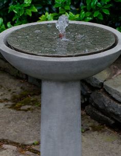 a concrete bird bath with water pouring from it