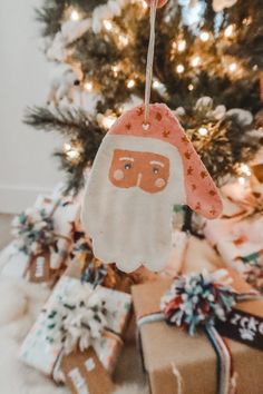 an ornament hanging from a christmas tree with presents under it and a gift wrapped in brown paper