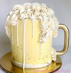 a yellow cake with white frosting and flowers on top is sitting on a gold plate