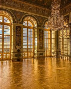 an empty ballroom with chandelier and large windows