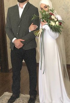 a man and woman standing next to each other in front of a mirror holding flowers