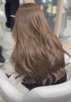 the back of a woman's head with long, wavy hair in a salon