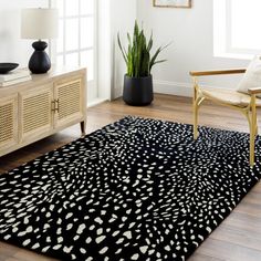 a black and white area rug in a living room with a chair, potted plant and window