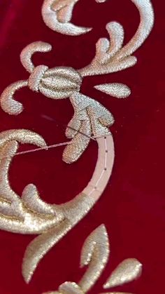 the design is made out of silver thread and sequins on a red background