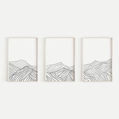 three framed artwork pieces on a wall with mountains drawn in black and white inks