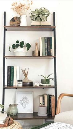 a shelf with books and plants on it in the corner of a room next to a couch