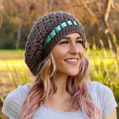 a woman with pink hair wearing a knitted beanie and smiling at the camera