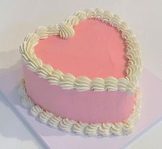 a heart - shaped cake with white icing and pink frosting