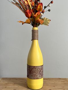 a yellow vase with flowers in it sitting on a table