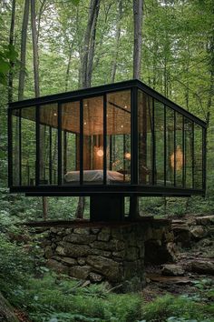 a glass house in the woods surrounded by trees