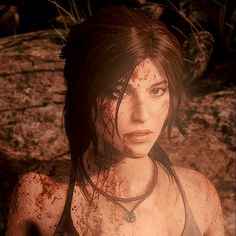 a woman with blood all over her face and chest standing in front of some rocks