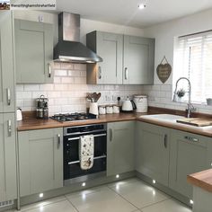 a kitchen with grey cabinets and wooden counter tops