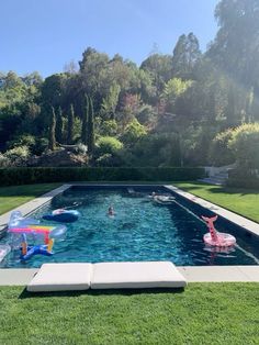 an inflatable pool with people swimming on it and floating toys near the edge