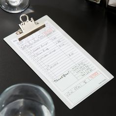 a close up of a clip board on a table next to a glass of water