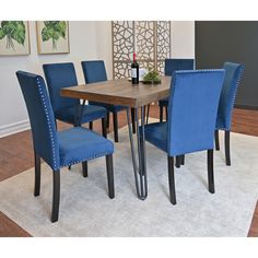 a dining room table with blue chairs and a wine bottle on the end table in front of it