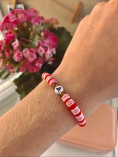 a person wearing a red and white bracelet with a cat in the hat bead