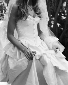 black and white photograph of a bride in her wedding dress sitting on the ground wearing a veil