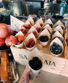 a person holding up a paper cup filled with berries