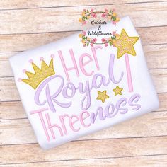 a white t - shirt with the words her royal threeness written in pink and gold