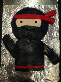 a cake that is shaped like a person wearing a red hat and black coat, on tin foil