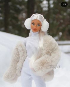 a barbie doll is standing in the snow wearing a white outfit and fur coat with her hands on her hips