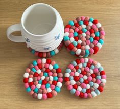 three coasters made out of felt sitting next to a coffee cup on a table