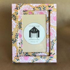 a photo frame with a flower pattern and a barn on the front in pink, green, yellow and white