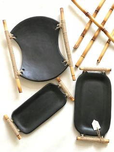 two black plates with bamboo sticks sticking out of them next to each other on a white surface