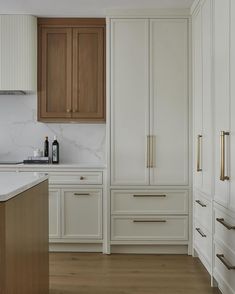 a kitchen with white cabinets and wood floors