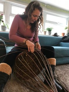 a woman sitting on the floor working with some wire