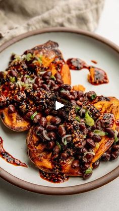 a white plate topped with black beans covered in sauce