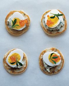 four crackers topped with eggs and cheese on top of a white tableclothed surface