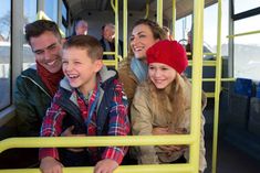 a group of people riding on the back of a bus with their arms around each other