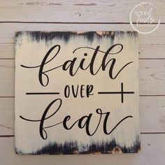 a wooden sign that says faith over fear on the side of a white wood wall