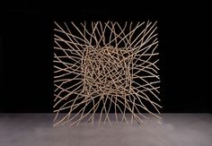 a sculpture made out of sticks in the middle of a dark room with black walls