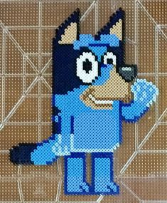 an image of a blue dog made out of perler beads on a tile background