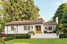 a white house surrounded by lush green trees and bushes in front of it is shown