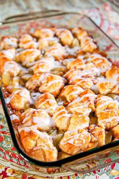 a casserole dish filled with cinnamon rolls covered in icing and drizzled