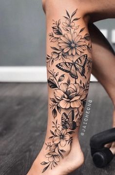 a woman's leg with flowers and butterflies on it, while she has her legs tattooed