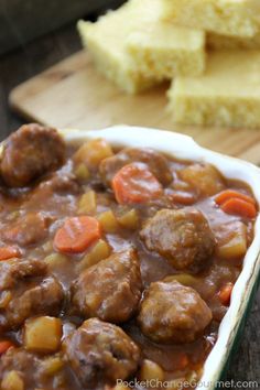 meatball stew in a white dish with carrots and gravy on the side