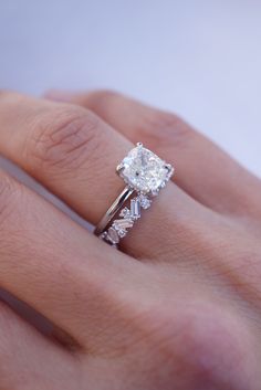 a woman's hand with a diamond ring on top of her finger and an engagement band