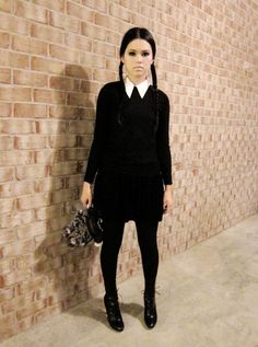 a woman standing in front of a brick wall with her handbag on her hip